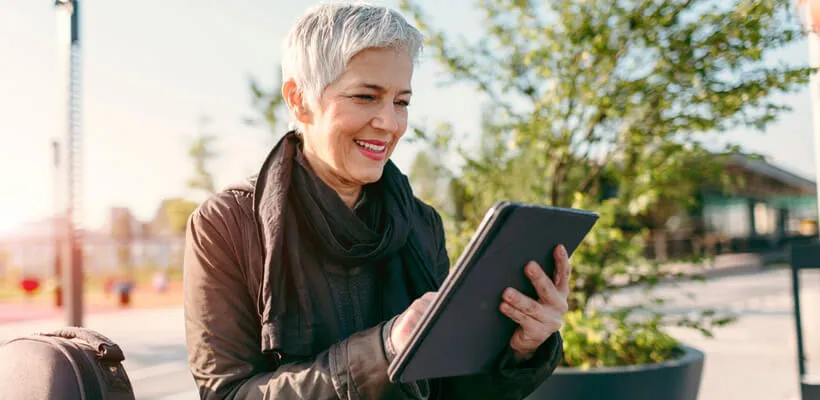 Žena stojaca na ulici a pozerajúca sa na svoj tablet