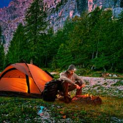 Wanderer mit Zelt und Trekkingsrucksack am Lagerfeuer