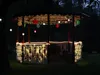 A gazebo decorated with lights and lanterns at night. Podgląd zdjęcia produktu
