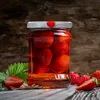 A jar of strawberries in syrup on a wooden surface. Podgląd zdjęcia produktu