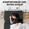A woman is sleeping on a dark gray sofa bed, with a cat nearby. Produktbild-Vorschau