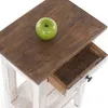 A close-up view of a wooden side table with an open drawer and a green apple on top. Náhled obrázku produktu