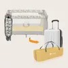 A travel cot is shown folded into a bag, with an arrow indicating it is being placed into a suitcase. Podgląd zdjęcia produktu