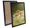 Two black picture frames are shown. One frame is in the foreground and displays a picture of a person and a dog. The other frame is behind the first and shows its backing. Produktbild-Vorschau