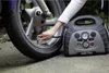 A person is using a portable air compressor to inflate a motorcycle tire. Podgląd zdjęcia produktu