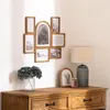 A wooden multi-photo frame is mounted on a wall above a wooden dresser. A lamp and a small framed picture are on the dresser. Náhled obrázku produktu