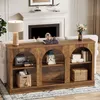 A long, rustic wooden console table with arched compartments, placed behind a sofa in a living room setting, with a fireplace in the background. Voir les images du produit