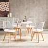 A dining set with a round white table and four white chairs with wooden legs, placed in a room with a modern gray wall and a dresser. Náhled obrázku produktu
