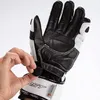 A hand is shown adjusting the strap of a black and white motorcycle glove. Podgląd zdjęcia produktu