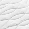 A close-up, abstract view of a white quilted fabric, likely a mattress or mattress topper, showing the texture and stitching pattern. Produktbild-Vorschau