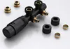 A close-up, studio shot of a black plumbing manifold with gold fittings, surrounded by some of its accessories, set against a light gray and white gradient background. Produktbild-Vorschau