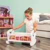 A young girl is playing with a doll crib next to a dollhouse. Produktbild-Vorschau