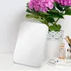 A white makeup mirror is placed on a white surface next to a potted hydrangea plant and some makeup accessories. Produktbild-Vorschau