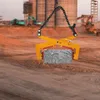 A construction site with heavy machinery and a stone being lifted by a clamp. Náhled obrázku produktu