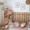 A nursery room with a wooden shelf unit, dolls in cribs, and decorative items. Anteprima dell’immagine prodotto