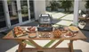 A table laden with food and a grill is set up on a patio. Voir les images du produit