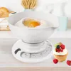 A white mechanical kitchen scale with a bowl containing flour and an egg, with a cupcake decorated with berries in the foreground. Voir les images du produit
