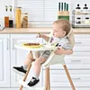 A baby is sitting in a high chair and eating. Produktbild-Vorschau
