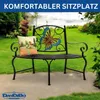 A metal garden bench with a butterfly design on the back, placed in a garden setting with a pillow on it. Anteprima dell’immagine prodotto