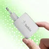 A hand holds a white Belkin dual USB-C charger against a green triangular pattern background. Náhľad obrázku produktu