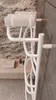 A white electric towel warmer is mounted on a wall in a bathroom, with towels draped over it. The background features a textured stone wall and a light-colored tiled wall. Náhľad obrázku produktu