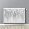 A radiator cover with a white leaf pattern is shown mounted on a gray wall above a wooden floor. Produktbild-Vorschau