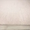 A close-up, low-angle view of a beige rug with a textured, melange appearance, resting on a light wooden floor. Produktbild-Vorschau