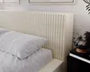 A close-up view of a beige upholstered bed frame with a pillow. Produktbild-Vorschau