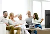 A multi-generational family is sitting on a couch and watching TV, with a young girl in the foreground interacting with a small device on a coffee table. Voir les images du produit
