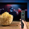 A hand holding a remote control in front of a TV screen with a bowl of popcorn. Voir les images du produit