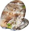 A toilet seat with a wooden texture and white floral pattern. Produktbild-Vorschau