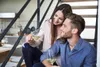 A couple sitting on stairs, holding wine glasses. Produktbild-Vorschau