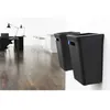 Two black wall-mounted trash bins are shown in a modern office or home environment with a wooden floor and desks in the background. Produktbild-Vorschau