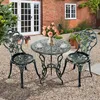A bistro set with a round table and two chairs is placed on a gravel patio in front of a brick building with white double doors and a window. Produktbild-Vorschau