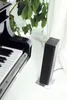 A black heater is placed next to a piano, with green plants and white curtains in the background. Náhľad obrázku produktu