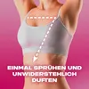 A person's torso wearing a white sports bra against a pink background, with dashed lines indicating application points for a spray. Anteprima dell’immagine prodotto