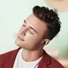 A man wearing earbuds and a red jacket, with his eyes closed. Voir les images du produit