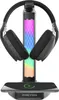 A black headphone stand with RGB lighting, holding a pair of black headphones, and a smartphone charging on its base. Produktbild-Vorschau