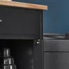A close-up view of a black kitchen cart with a wooden countertop, showing a drawer and a cabinet hinge. Produktbild-Vorschau