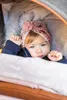 A baby lying in a stroller, wrapped in blankets and wearing a hat. Náhled obrázku produktu