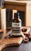 A bottle of vanilla extract is placed on a wooden board with vanilla beans, cinnamon sticks, and star anise. Náhled obrázku produktu