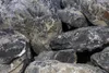 A close-up view of a pile of large, rough, dark gray and black rocks with white veining. Produktbild-Vorschau