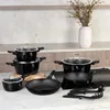 A collection of black cookware set on a countertop with a vase of flowers in the background. Anteprima dell’immagine prodotto