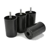 Four black furniture feet with threaded bolts are arranged on a white background. One foot is lying on its side in the foreground, while three are standing upright behind it. Voir les images du produit