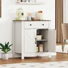 A white and brown sideboard cabinet with a drawer and two doors, placed in a room with white paneled walls and a wooden floor. Náhľad obrázku produktu