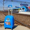 A blue Paw Patrol suitcase sits on train tracks next to a train at a station. Náhľad obrázku produktu