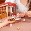 A miniature bakery scene with detailed pastries and display cases, being interacted with by hands. Podgląd zdjęcia produktu