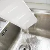 Water is being poured from a white plastic tray into a stainless steel sink. Náhľad obrázku produktu