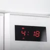 A close-up view of a white built-in microwave's digital display showing the time and a heating icon. Anteprima dell’immagine prodotto