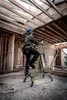 A construction worker is using a green ladder inside a building under construction. Podgląd zdjęcia produktu